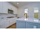 Modern kitchen with white cabinets, stainless steel appliances, and a blue island at 3731 Tea Leaf Aly, Land O Lakes, FL 34638