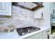 Gas cooktop with stone backsplash in a bright kitchen at 3731 Tea Leaf Aly, Land O Lakes, FL 34638