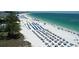 Aerial view of beach with rows of lounge chairs and umbrellas on the white sand at 3302 E Maritana Dr, St Pete Beach, FL 33706