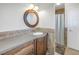 Bathroom features a round wood-framed mirror, a vanity with a gray countertop, and a shower-tub combination at 3302 E Maritana Dr, St Pete Beach, FL 33706