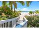 Beach access showing lush greenery, flowers, palms, and a glimpse of the sandy beach at 3302 E Maritana Dr, St Pete Beach, FL 33706