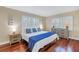 Sunlit bedroom features wood floors, plantation shutters, and stylish coastal decor with blue and white accents at 3302 E Maritana Dr, St Pete Beach, FL 33706