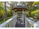 Charming gazebo with white railings, a wooden walkway, and lush landscaping creates a serene outdoor retreat at 3302 E Maritana Dr, St Pete Beach, FL 33706
