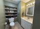 Cozy bathroom featuring floating shelves, a mirror, neutral-toned walls, and a single sink vanity with white cabinets at 345 Bayshore Blvd # 610, Tampa, FL 33606