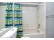 Clean, functional bathroom featuring a tub with shower, ceramic tiles, and bright striped shower curtain at 3454 Hillmoor Dr, Palm Harbor, FL 34685