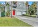 Two-story townhome with attached two-car garage, red door, and tropical landscaping at 411 S Fremont Ave # B, Tampa, FL 33606