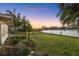 Tranquil backyard with lush lawn, mature palms, and sunset views over the channel at 52 Sandpiper Rd, Tampa, FL 33609