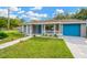 Newly renovated home with gray exterior, teal garage door, and landscaped front yard at 5718 Orange Grove Ave, New Port Richey, FL 34652