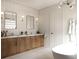 Stylish bathroom featuring double sinks, modern lighting, a soaking tub, and a large mirror at 7176 S Shore Dr, South Pasadena, FL 33707