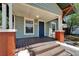 Charming covered front porch with red brick columns and a wooden deck at 1312 E Louise Ave, Tampa, FL 33603