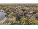 Aerial view of a home with a screened pool, lush landscaping, and a lake in the background at 13811 Shady Shores Dr, Tampa, FL 33613