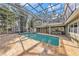Spacious pool with screened enclosure, travertine decking, and view of the two-story home and lush landscaping at 13811 Shady Shores Dr, Tampa, FL 33613