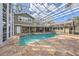 Backyard pool, partially enclosed and screened-in, with attached hot tub, travertine decking, and green home exterior at 13811 Shady Shores Dr, Tampa, FL 33613