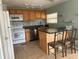 Galley kitchen with wood cabinets, mosaic backsplash, and island with seating at 12501 Ulmerton Rd # 119, Largo, FL 33774
