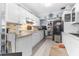 Bright kitchen featuring white cabinetry, modern appliances, tile backsplash, and light wood-look flooring at 225 35Th N St, St Petersburg, FL 33713