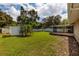 Backyard with grassy lawn, shed, screened patio, and mature trees at 4491 Shore Acres Ne Blvd, St Petersburg, FL 33703