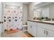 Bathroom featuring double sinks, white cabinets, and a shower with a patterned curtain at 9407 Channing Hill Dr, Ruskin, FL 33573