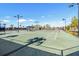 Well-lit tennis courts with an awning, picnic tables, and a black chainlink fence in the background at 9407 Channing Hill Dr, Ruskin, FL 33573