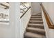 Carpeted staircase with white spindles and stained wood railing at 17525 Glistening Ct, Venice, FL 34293