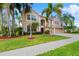 Two-story house with a tan exterior, red door, palm trees, and a well-manicured lawn at 1858 Longview Ln, Tarpon Springs, FL 34689