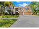 Two-story house with a tan exterior, three-car garage, palm trees, and a landscaped lawn at 1858 Longview Ln, Tarpon Springs, FL 34689