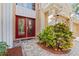 Inviting entryway with red double doors, stone walkway, and lush landscaping at 1858 Longview Ln, Tarpon Springs, FL 34689
