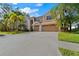 Two-story house with a tan exterior, three-car garage, palm trees, and a long driveway at 1858 Longview Ln, Tarpon Springs, FL 34689