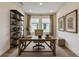 Well-lit home office features a wooden desk, tufted chair, and ample bookshelf space at 18096 Foxtail Loop, Venice, FL 34293