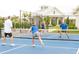Active pickleball game in progress on a bright blue court, surrounded by well maintained fencing and landscaping at 18096 Foxtail Loop, Venice, FL 34293