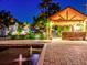 Evening view of a brick paved patio with a pergola and water features at 518 Riverside Dr, Tarpon Springs, FL 34689