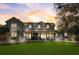 Elegant two-story home with a covered porch, lush lawn, and manicured landscaping at sunset at 518 Riverside Dr, Tarpon Springs, FL 34689