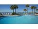 Resort pool with blue lounge chairs and palm trees at 5500 Gulf Blvd # 2235, St Pete Beach, FL 33706