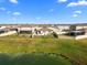 Aerial view of houses and a crystal-blue lagoon at 8968 Parsons Hill Blvd, Wesley Chapel, FL 33545