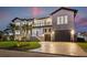 Elegant two-story home with a paved driveway, lush lawn, and a three-car garage at twilight at 1954 Iowa Ne Ave, St Petersburg, FL 33703