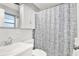 Clean bathroom with a white vanity, toilet, and shower featuring a stylish curtain and functional storage cabinet at 200 Glennes Ln # 111, Dunedin, FL 34698