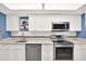 Modern kitchen featuring stainless steel appliances, white cabinetry, and blue walls with a charming giraffe portrait at 200 Glennes Ln # 111, Dunedin, FL 34698