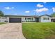 Inviting home with a well-maintained lawn, a sleek black garage door, and updated solar panels at 2132 Academy Dr, Clearwater, FL 33764