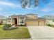Two-story house with tan exterior, three-car garage, and manicured lawn at 2622 Bonterra Blvd, Valrico, FL 33594