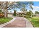 House exterior featuring a brick driveway, landscaping, and large tree at 6200 Bahama Shores S Dr, St Petersburg, FL 33705