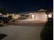 Night view of a home with a well-lit driveway and manicured landscaping at 212 Poinciana Ln, Largo, FL 33770