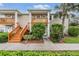 Tan two-story condo with wooden stairs, balcony, and landscaping at 9016 Shallowford Ln # 202, Port Richey, FL 34668
