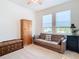 Well-lit bedroom with a sofa bed, wooden storage, and two windows at 13444 Golden Lime Ave, Spring Hill, FL 34609