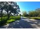 Long paved driveway with trees and lush green grass on either side at 2098 Belleair Rd, Clearwater, FL 33764