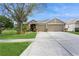 Tan house with lush landscaping, a three-car garage, and a spacious yard at 1433 Emerald Hill Way, Valrico, FL 33594