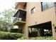 Exterior view of a building showing balconies, parking garage, and lush greenery at 3076 Eastland Blvd # 106, Clearwater, FL 33761