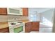 Open kitchen view to the living room area, featuring wooden cabinets and a white oven at 3076 Eastland Blvd # 106, Clearwater, FL 33761