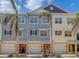 Three-unit townhouse building, featuring a blend of yellow and gray siding, and palm trees at 94 The Cove Way, Indian Rocks Beach, FL 33785