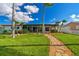 Exterior view of a waterfront home with lush lawn and stone pathway leading to the patio at 11683 Grove St, Seminole, FL 33772