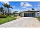 Modern home featuring a glass garage door, lush landscaping, and a brick paver driveway at 11683 Grove St, Seminole, FL 33772