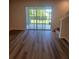 Open-concept living room with wood-look flooring, sliding glass doors to the backyard, and stairwell at 2472 Mellow Ln, Clearwater, FL 33765